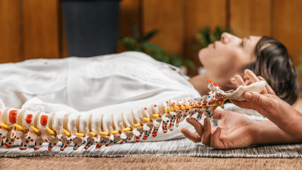 Woman laying down with spine model next to her